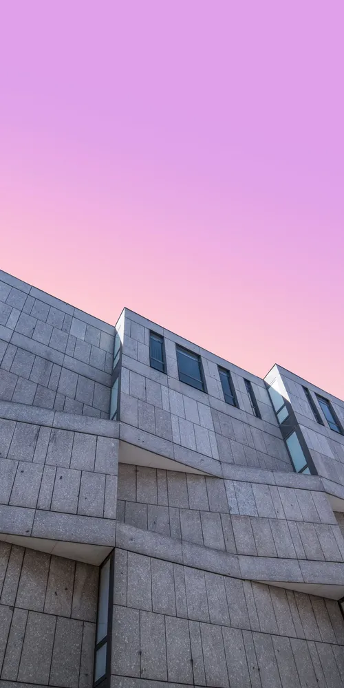 Geometric concrete building beneath a pink sky